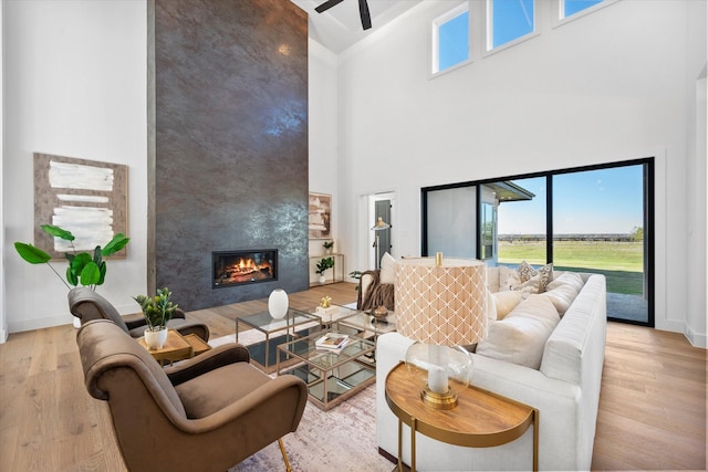 living area featuring a fireplace, wood finished floors, high vaulted ceiling, and a healthy amount of sunlight
