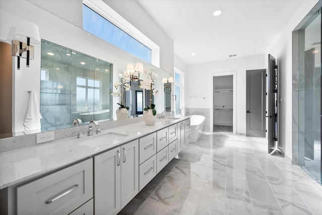 bathroom featuring marble finish floor, a freestanding tub, a sink, and double vanity
