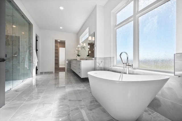 bathroom featuring a healthy amount of sunlight, marble finish floor, vanity, and a stall shower