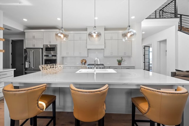 kitchen featuring light countertops, hanging light fixtures, dark wood-style flooring, and stainless steel appliances