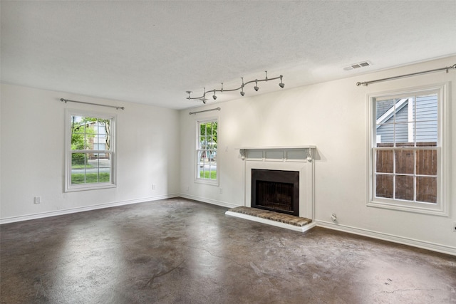 unfurnished living room with a textured ceiling, concrete flooring, a fireplace, baseboards, and visible vents