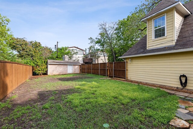 view of yard with a fenced backyard, an outdoor structure, and a storage shed