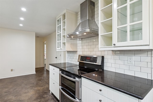 kitchen with wall chimney exhaust hood, tasteful backsplash, range with two ovens, and baseboards