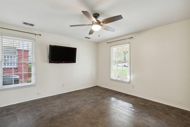 unfurnished room with concrete flooring, visible vents, a ceiling fan, and baseboards