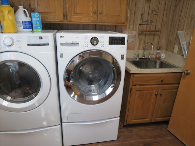 laundry area featuring dark wood finished floors, cabinet space, washing machine and clothes dryer, and a sink