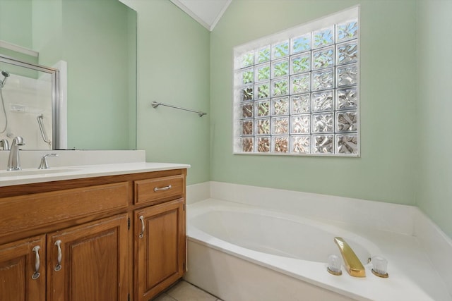 bathroom featuring vaulted ceiling, a shower stall, crown molding, a garden tub, and vanity