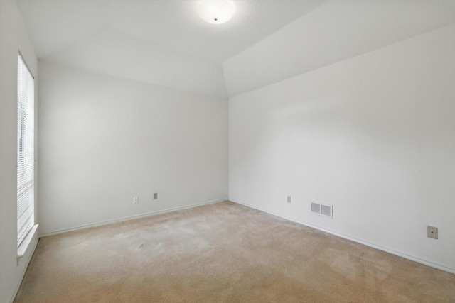 carpeted empty room with lofted ceiling, visible vents, and baseboards