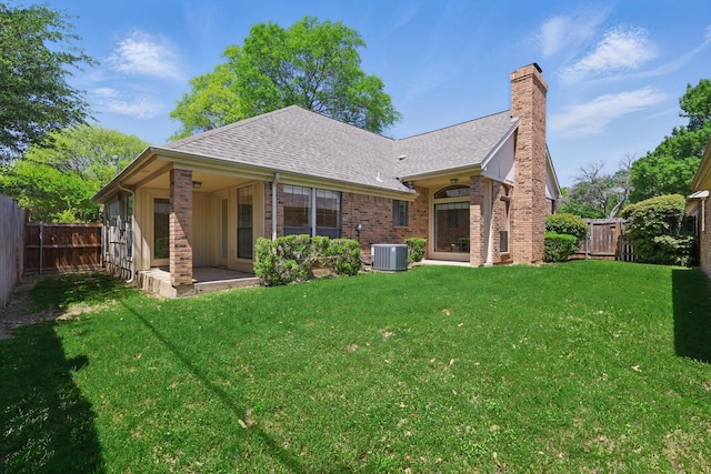 back of property featuring a lawn, roof with shingles, a chimney, and a fenced backyard