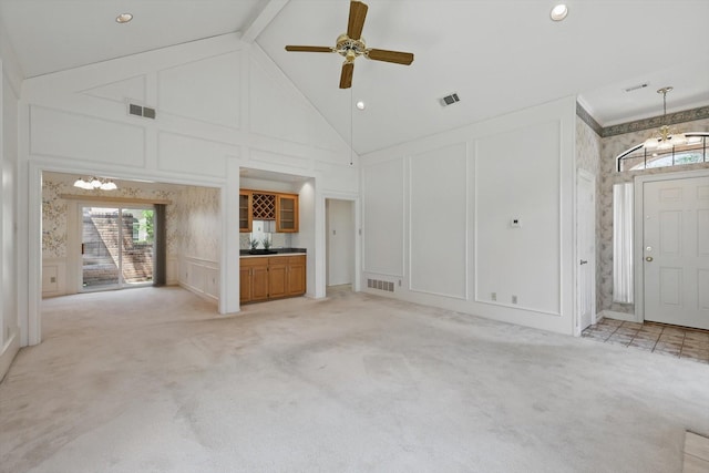 unfurnished living room featuring light colored carpet, a decorative wall, high vaulted ceiling, and visible vents
