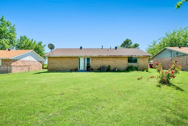 back of house featuring fence, a lawn, and brick siding