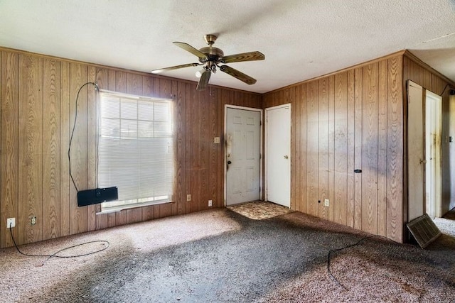 interior space with ceiling fan, wood walls, and carpet flooring