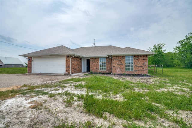 ranch-style house with an attached garage, driveway, brick siding, and roof with shingles