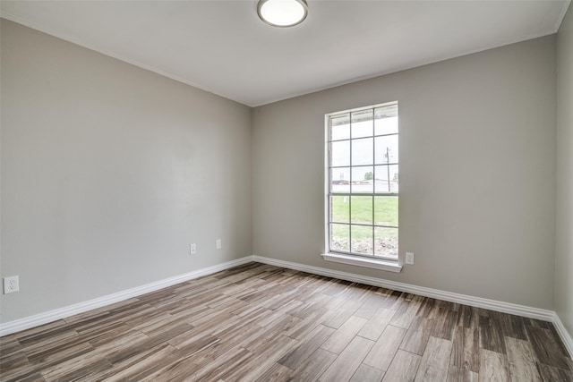 spare room with baseboards, crown molding, and wood finished floors