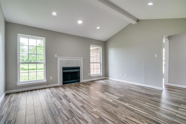 unfurnished living room featuring lofted ceiling with beams, baseboards, recessed lighting, wood finished floors, and a fireplace