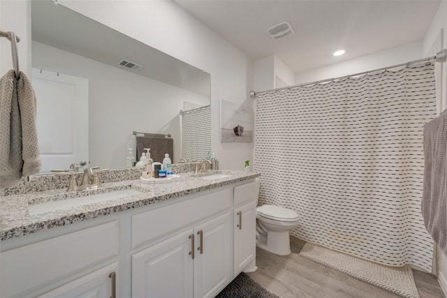 full bathroom featuring visible vents, a sink, wood finished floors, and toilet