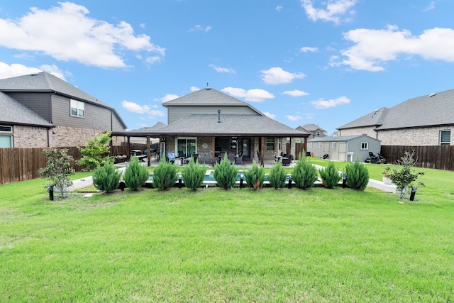 back of property with a lawn, roof with shingles, a fenced backyard, and a patio area