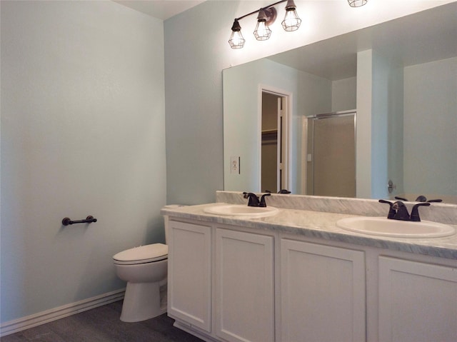920 Kendall Dr, Arlington, TX 76001 - bathroom featuring toilet, a shower stall, double vanity, wood finished floors, and baseboards