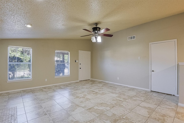 spare room featuring a textured ceiling, visible vents, a ceiling fan, and baseboards