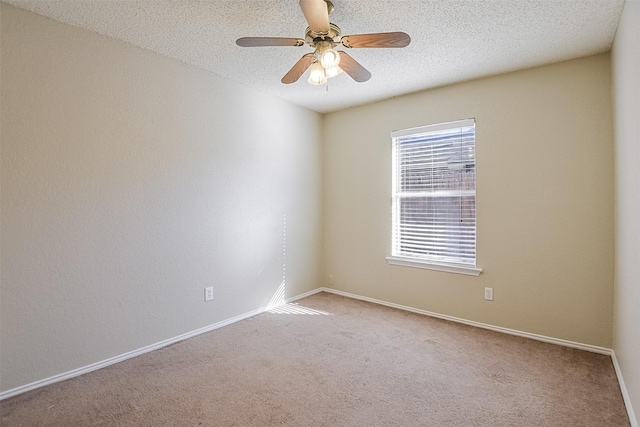 carpeted spare room with ceiling fan, baseboards, and a textured ceiling