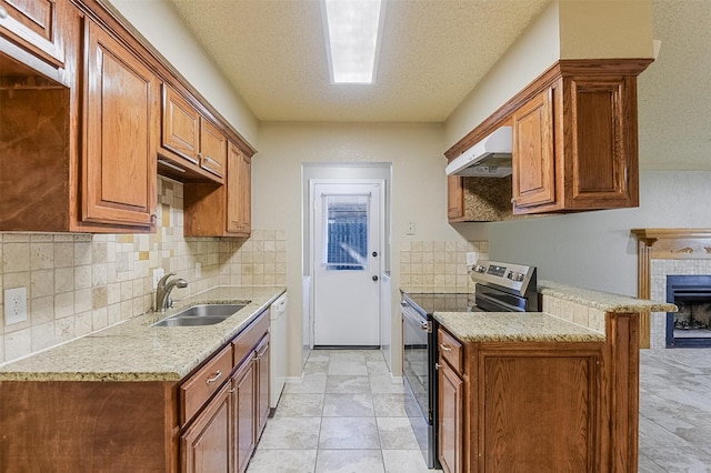 kitchen featuring electric stove, a sink, decorative backsplash, brown cabinets, and under cabinet range hood