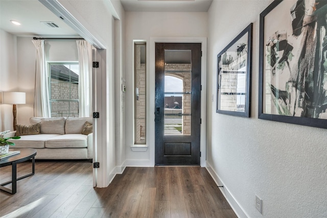 foyer entrance with baseboards, visible vents, a textured wall, and dark wood-style floors