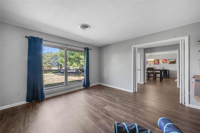 interior space featuring wood finished floors, a textured ceiling, baseboards, and visible vents