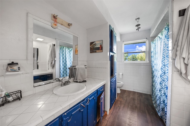full bathroom with toilet, tile walls, wainscoting, wood finished floors, and vanity