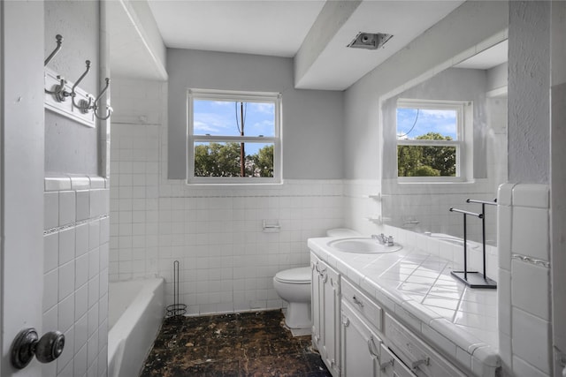 bathroom with toilet, a healthy amount of sunlight, vanity, and tile walls