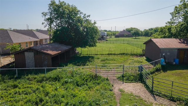 view of yard with fence, a rural view, and an outbuilding