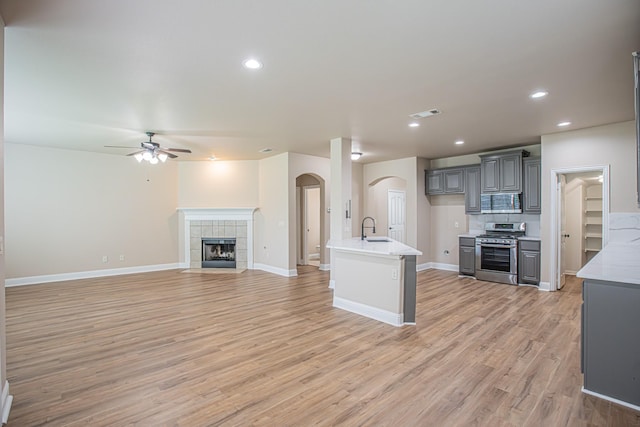 kitchen with ceiling fan, arched walkways, a sink, open floor plan, and stainless steel appliances