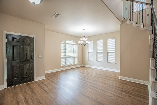 foyer entrance featuring an inviting chandelier, baseboards, wood finished floors, and visible vents