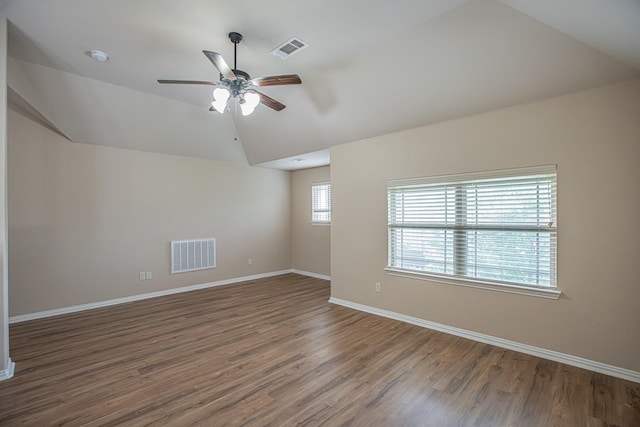 empty room featuring a ceiling fan, visible vents, wood finished floors, and lofted ceiling