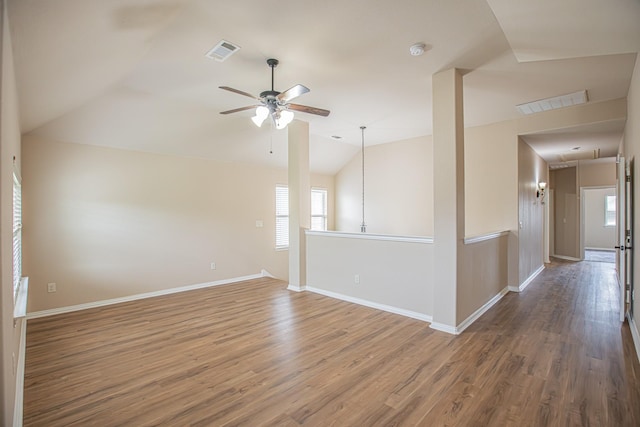 empty room featuring visible vents, ceiling fan, wood finished floors, and vaulted ceiling