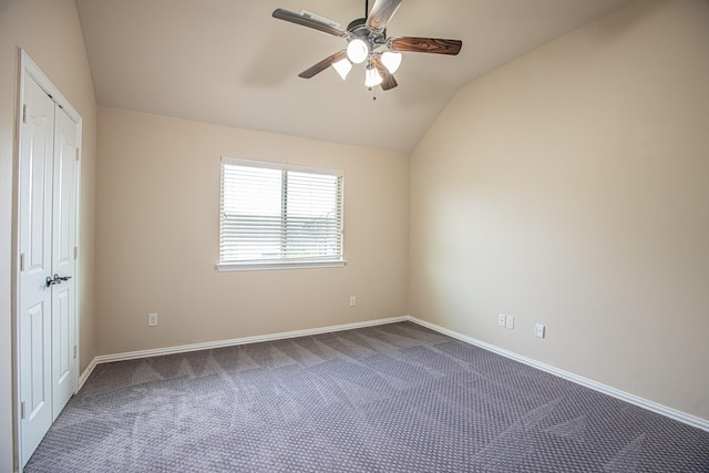 unfurnished bedroom with a closet, lofted ceiling, dark carpet, baseboards, and ceiling fan