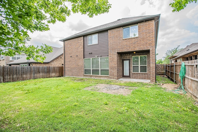 rear view of house with brick siding, a fenced backyard, a lawn, and a patio