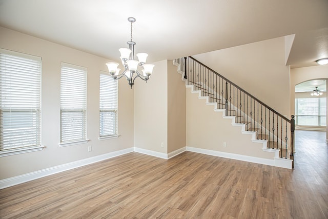 interior space with stairs, baseboards, wood finished floors, and ceiling fan with notable chandelier