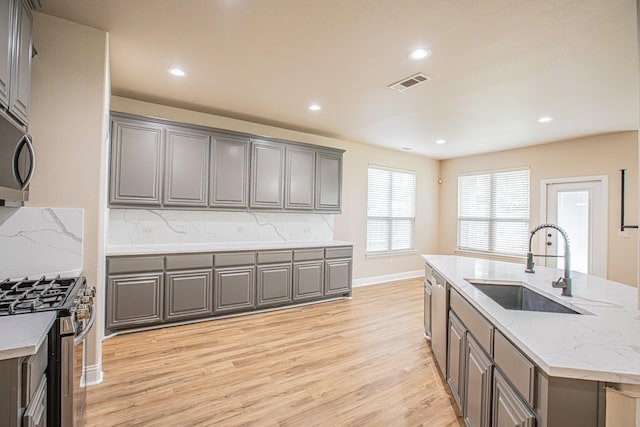 kitchen featuring visible vents, a sink, gray cabinetry, and stainless steel appliances