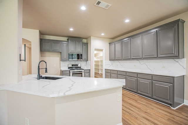 kitchen with gray cabinets, visible vents, light wood-type flooring, a sink, and stainless steel appliances