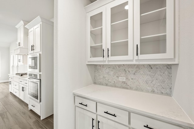2708 Creekhollow Ct, Denton, TX 76226 - kitchen with stainless steel appliances, tasteful backsplash, white cabinetry, and glass insert cabinets