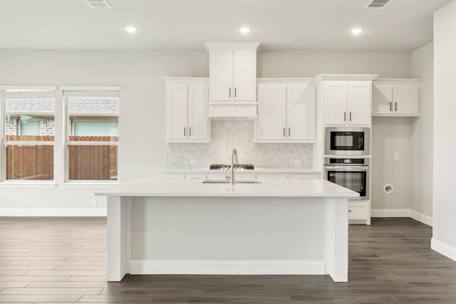 2708 Creekhollow Ct, Denton, TX 76226 - kitchen featuring appliances with stainless steel finishes, light countertops, dark wood-type flooring, decorative backsplash, and white cabinetry