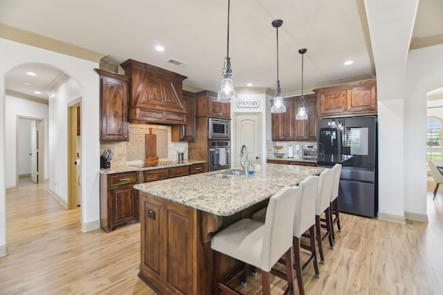 kitchen with appliances with stainless steel finishes, light wood-style floors, premium range hood, and baseboards
