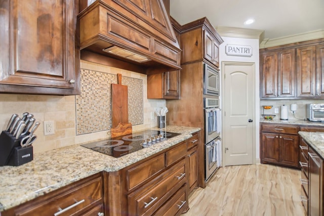 kitchen with custom exhaust hood, light stone countertops, black electric stovetop, and tasteful backsplash