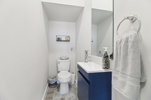bathroom featuring toilet, vanity, wood finished floors, and baseboards