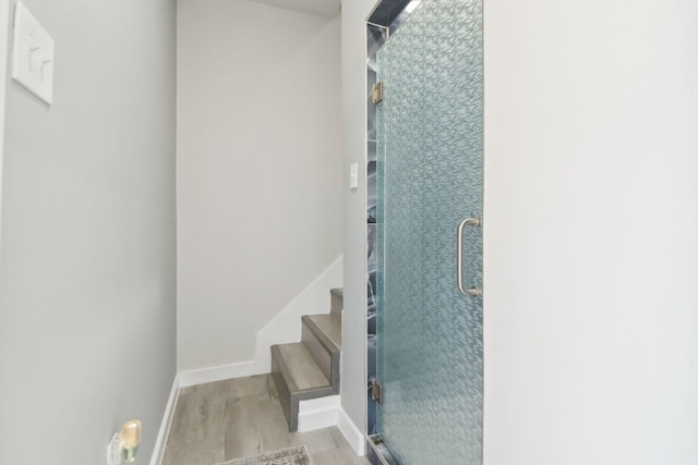 staircase featuring wood finished floors and baseboards
