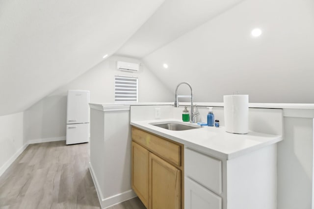 kitchen featuring light wood-style flooring, a sink, light countertops, a wall mounted AC, and vaulted ceiling