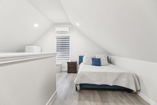 bedroom with baseboards, wood finished floors, and an AC wall unit