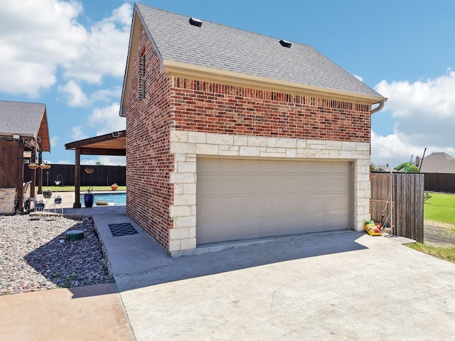 view of side of property featuring a garage, stone siding, a shingled roof, and brick siding
