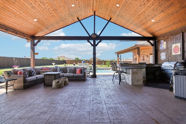 view of patio / terrace featuring fence, a fenced in pool, an outdoor hangout area, outdoor dry bar, and exterior kitchen