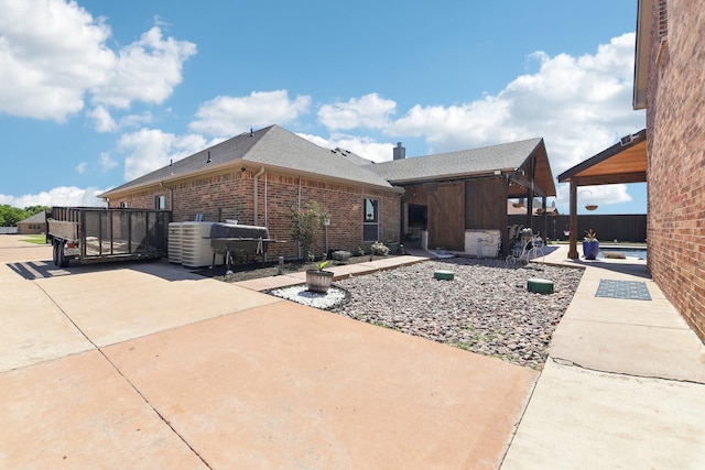 back of property with a chimney, brick siding, fence, a patio, and roof with shingles