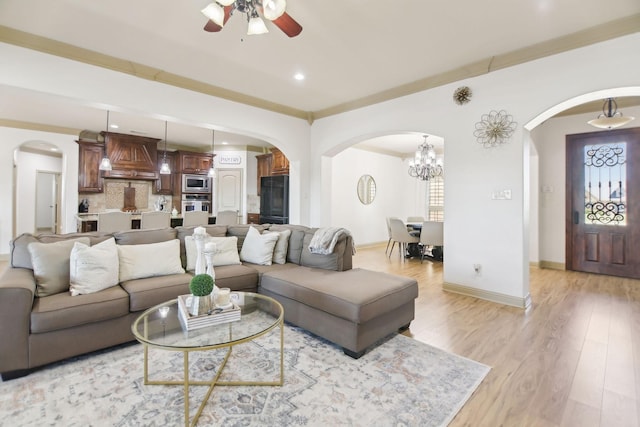 living area featuring arched walkways, ceiling fan, and light wood finished floors